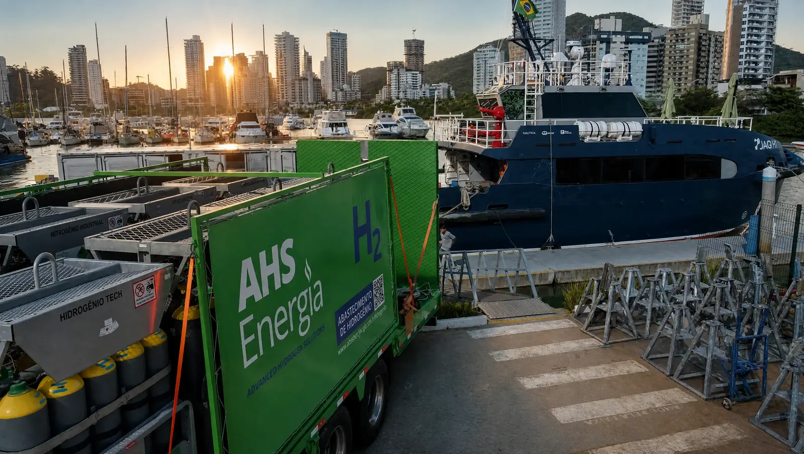 Caminhão de abastecimento de hidrogênio da AHS Energia ao lado da embarcação JAQ H1, com o horizonte de Balneário Camboriú ao fundo