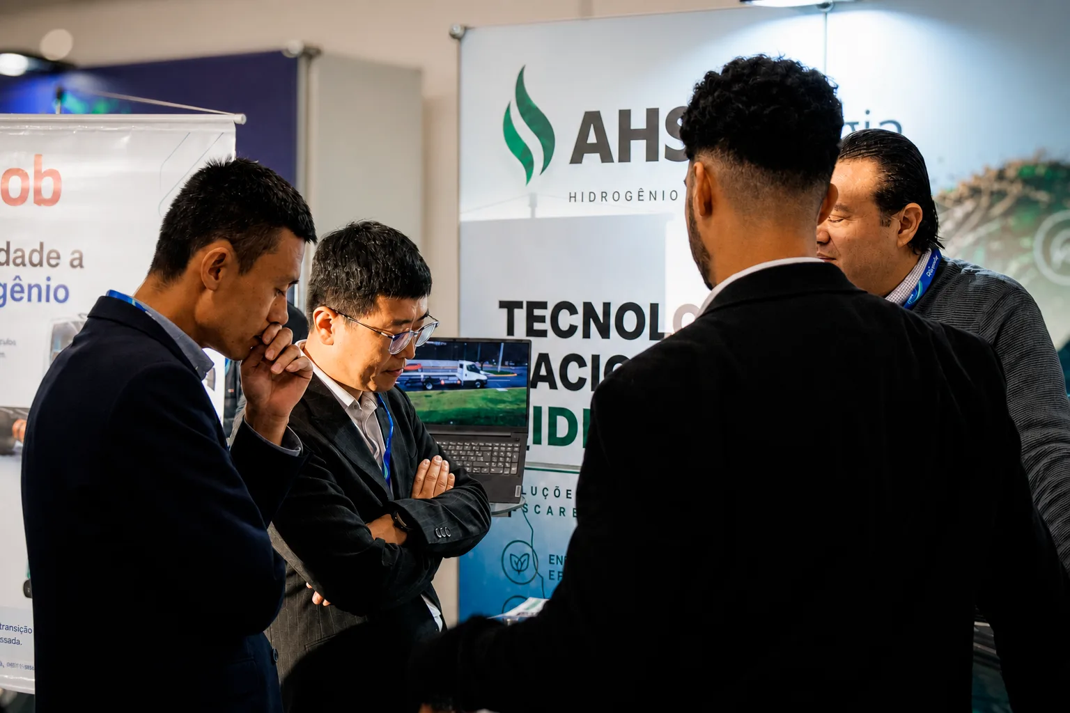 Visitantes observam apresentação de tecnologia da AHS Energia em laptop no estande